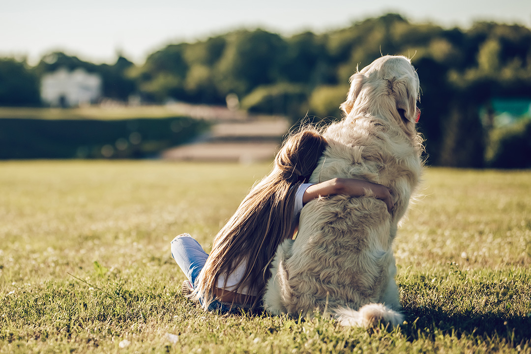 Child and dog sitting on hill