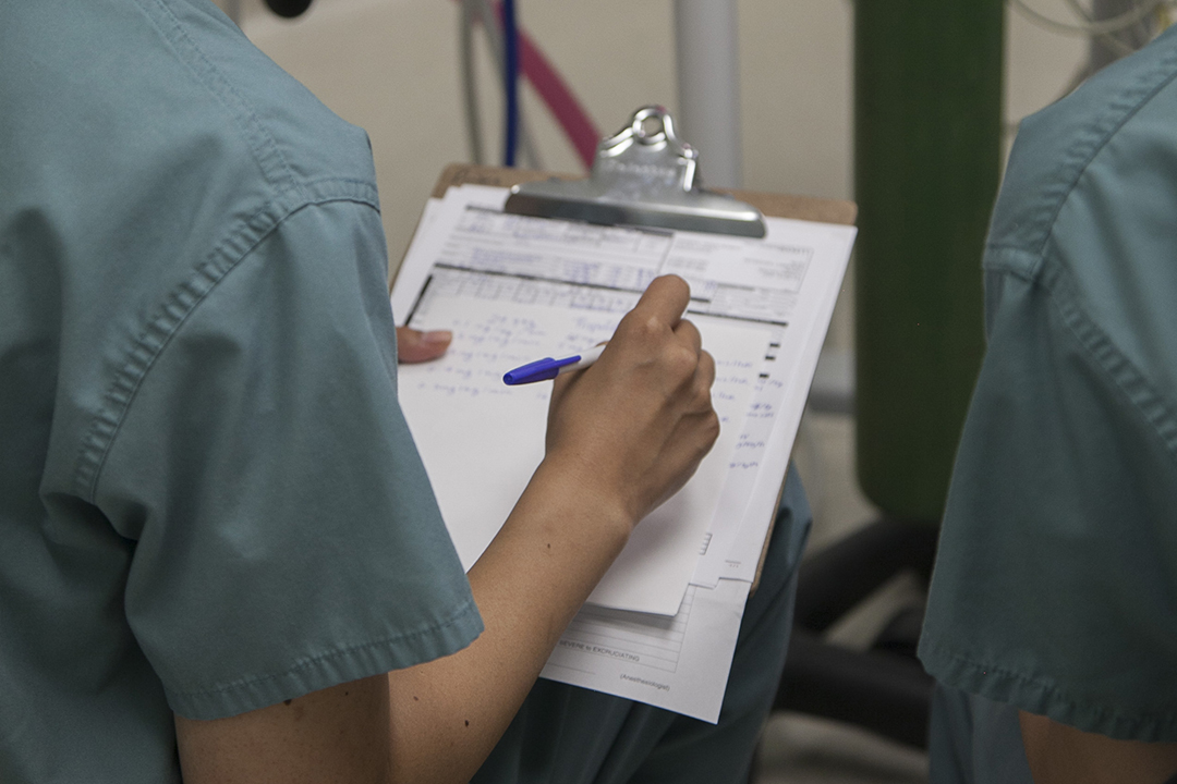 A clinical team member fills out a medical form during a surgery. 