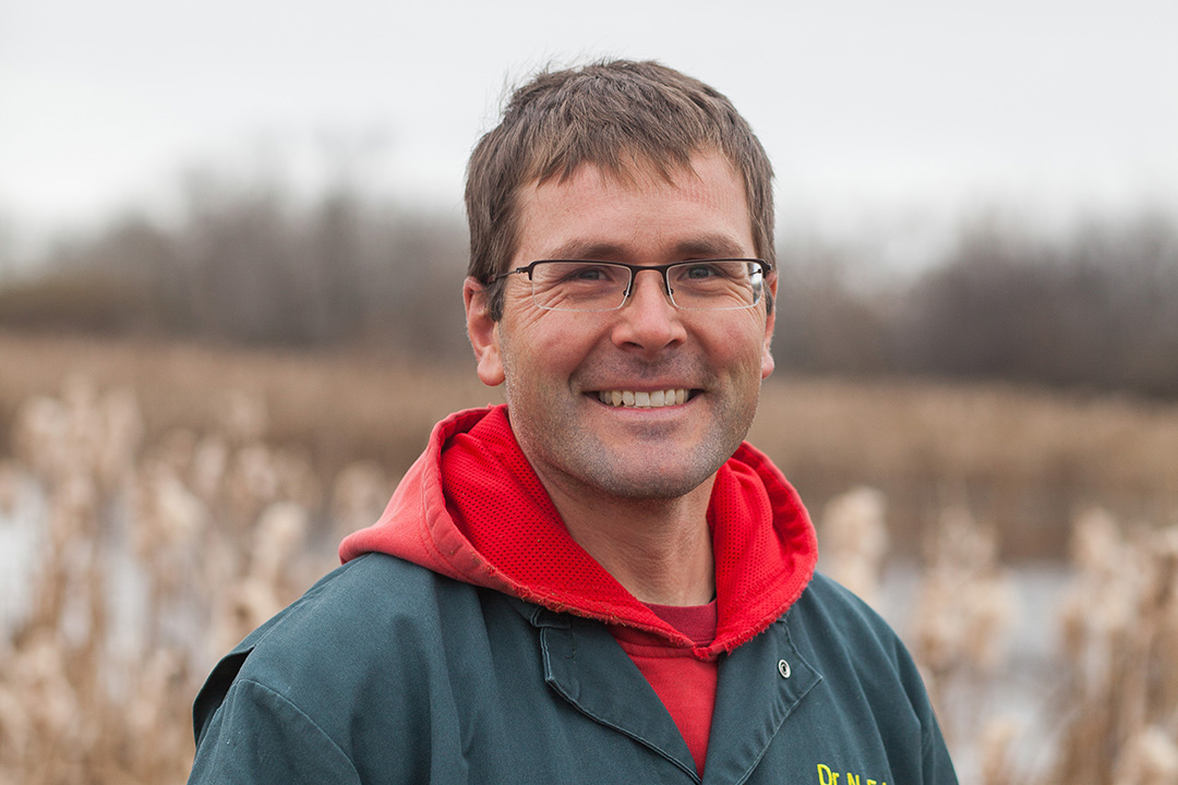 Man in coveralls standing in field